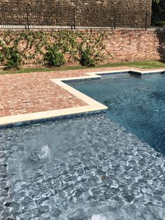 an empty swimming pool in front of a brick wall