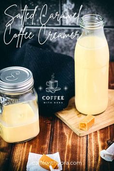 two mason jars filled with coffee creamer on top of a wooden table next to a cutting board