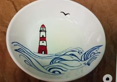 a bowl with a red and white lighthouse painted on the side, in front of a brown background