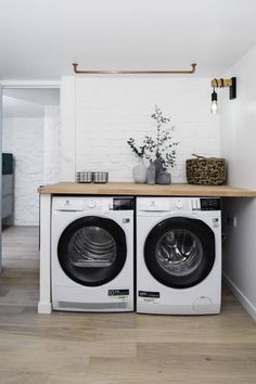 a washer and dryer in a room with white walls, wood floors and flooring