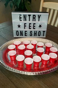 red cups are arranged on a platter in front of a sign that says entry fee oneshot