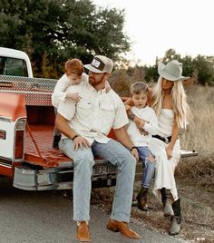 a family sitting on the back of a pickup truck