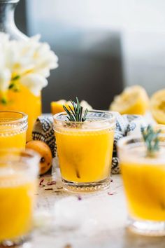 two glasses filled with orange juice and garnished with rosemary