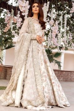 a woman in a white gown standing under flowers