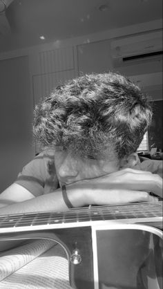 black and white photograph of a man with his head on the back of a guitar