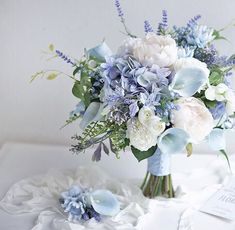 a bouquet of flowers sitting on top of a white table cloth next to a card