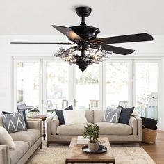 a living room with couches, chairs and a ceiling fan in the middle of it