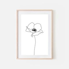 a black and white drawing of a single flower on a wall above a wooden frame