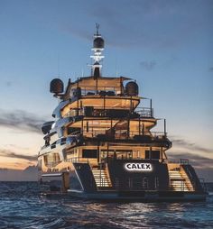 a large boat floating on top of the ocean at dusk with stairs leading up to it's upper deck