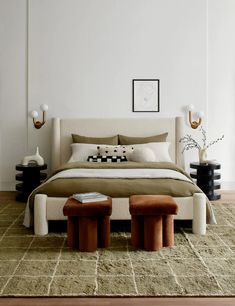 a large bed sitting on top of a wooden floor next to two stools in front of it