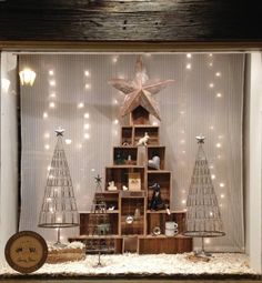 a christmas display in a window with lights on the windowsill and wooden shelves filled with ornaments