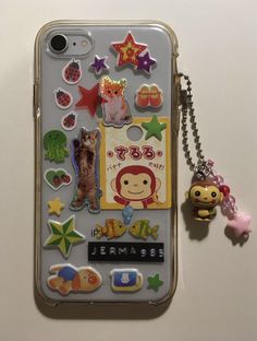 a cell phone with various stickers on it and a keychain attached to the back