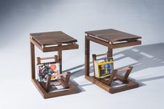 two wooden side tables with magazine holders on them, one holding magazines and the other holding books