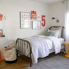 a bed room with a neatly made bed and pictures hanging on the wall above it