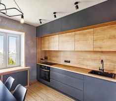 an empty kitchen with wooden cabinets and black counter tops, along with a window that looks out onto the city