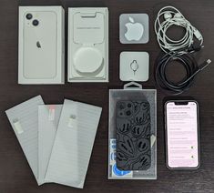 the contents of an apple phone are laid out on a table with cables, ear buds and other accessories