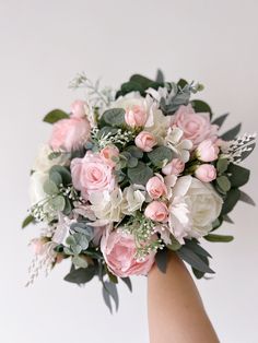 a bridal bouquet in someone's hand with pink and white flowers on it