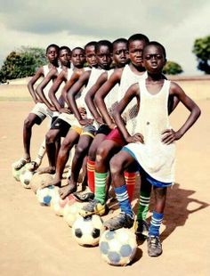 a group of young men standing next to each other on top of soccer balls