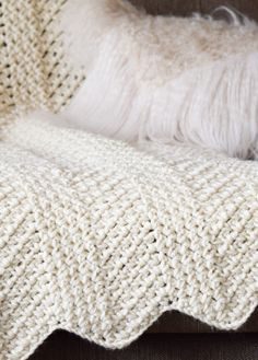 a white knitted blanket sitting on top of a couch