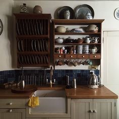 a kitchen filled with lots of wooden cabinets and dishes on top of shelves next to a sink