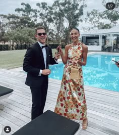 a man and woman standing next to each other in front of a pool