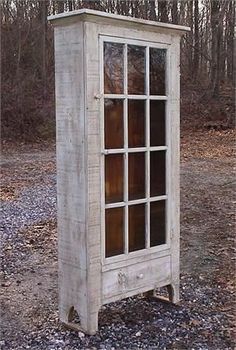 an old white cabinet sitting in the middle of a forest filled with trees and rocks