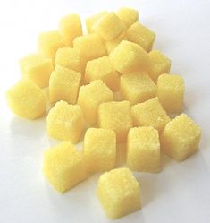 a pile of yellow sugar cubes sitting on top of a white table