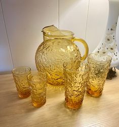 a glass pitcher and four glasses on a table