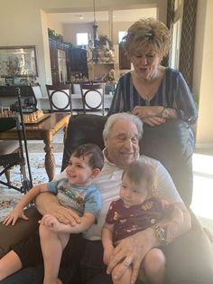 an older man, woman and two children sitting on a couch in a living room