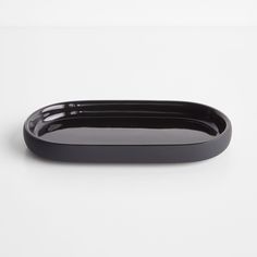 a black oval tray on a white surface with no one around it or someone else