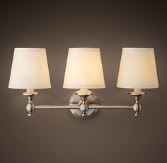 three lamps are on the wall in front of a mirror and lamp shade is off