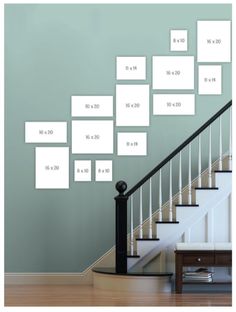 a stair case with multiple frames on the wall and below it is a set of stairs