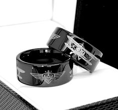 two black rings sitting on top of a white table next to each other with wings