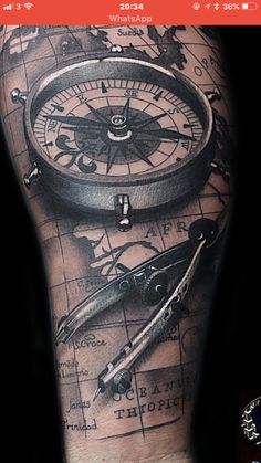 a man's arm with a compass tattoo on it and an arrow in the middle