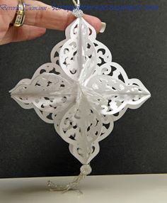 a hand holding a white ornament in the shape of a snowflake