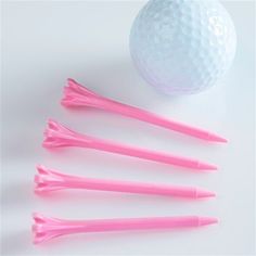 four pink golf tees next to a white ball