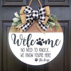 a welcome sign hanging on the front door with a dog's paw and checkered bow