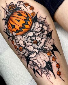 a woman's thigh with a pumpkin and flowers on it