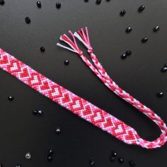 a red and white braided lanyard sitting on top of a black table next to beads