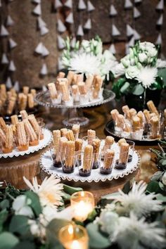 small desserts are arranged on trays with candles and flowers in the back ground