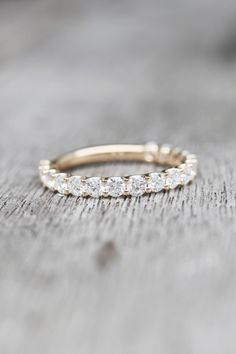 a gold wedding band with small diamonds on it sitting on top of a wooden table