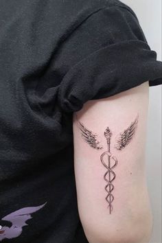 a woman with a tattoo on her arm has a cadus symbol tattooed on it