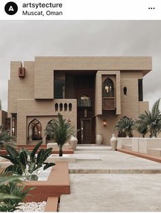 a large building with many windows and plants in the foreground on a cloudy day