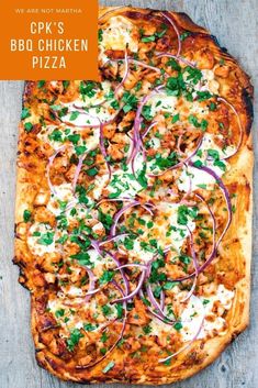 a square pizza with onions, cheese and parsley on the top is sitting on a wooden surface