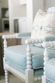 a white chair with blue and white pillows on it