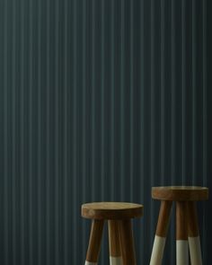 two wooden stools sitting next to each other in front of a wall with vertical blinds