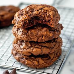 a stack of cookies sitting on top of a cooling rack next to two chocolate pieces