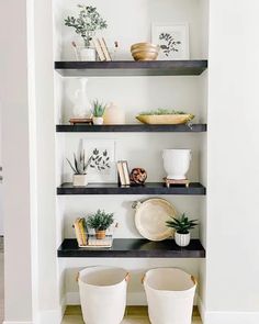 the shelves are filled with pots, bowls and other decorative items in white painted walls