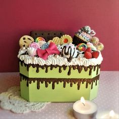 a cake with white frosting and lots of candies on it next to a lit candle