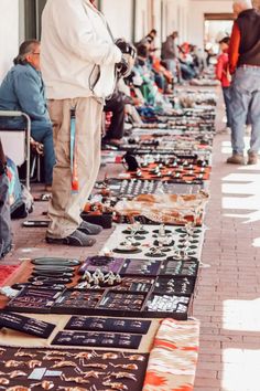 many people are sitting on the sidewalk and looking at various items that have been sold